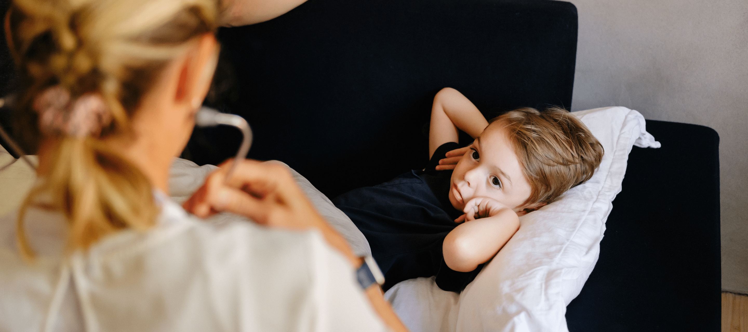 Lege hjemme i stua som undersøker barn på sofaen